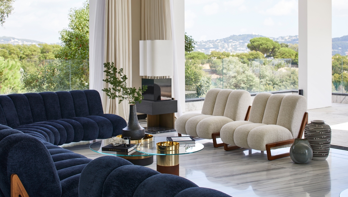 Humbert & Poyet Villa Odaya Mid-century Modern living room with glass coffee table and wraparound blue sofa