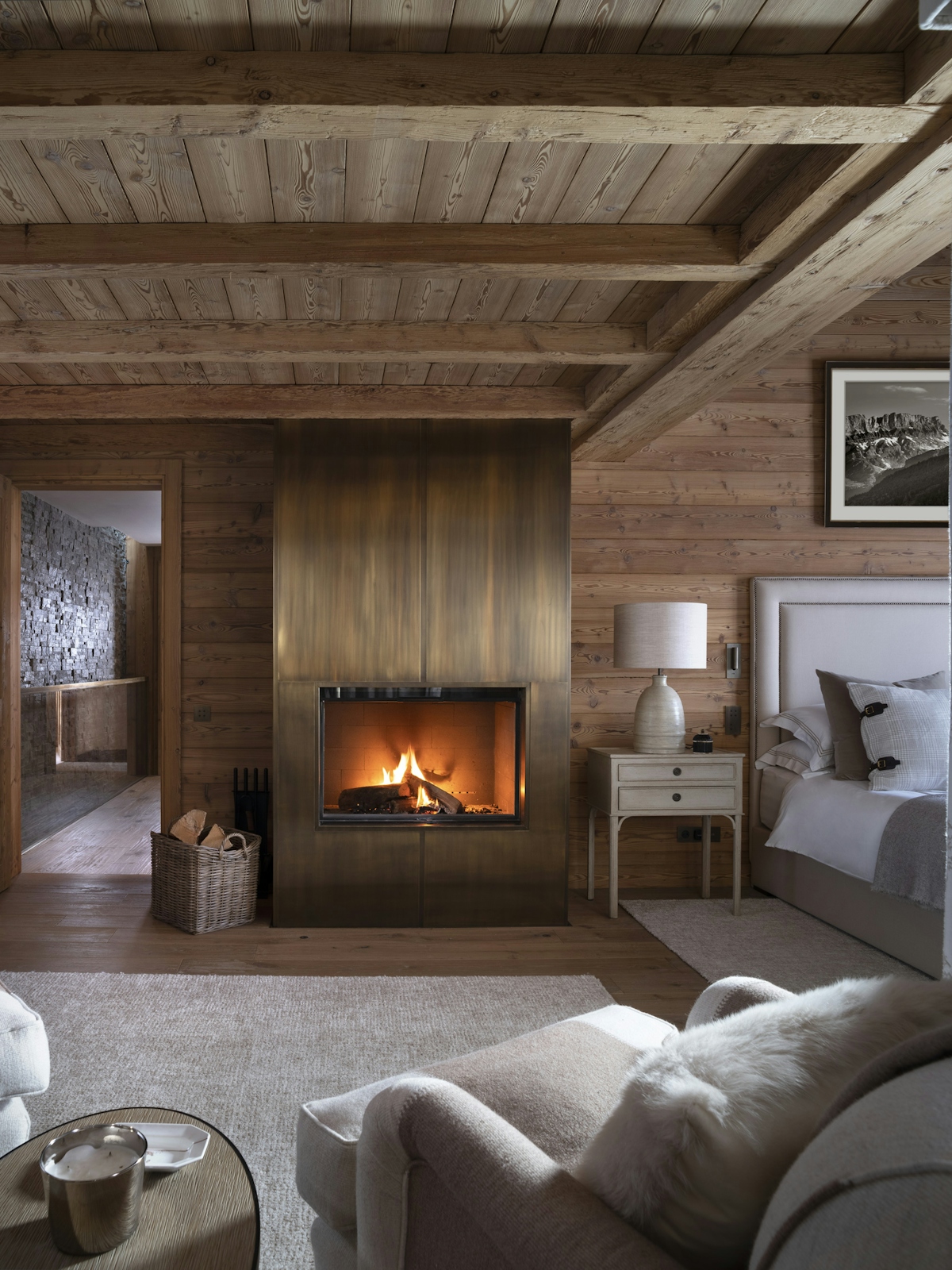 Nicky Dobree bedroom with open fireplace, textured cushions and rug with armchair and side table